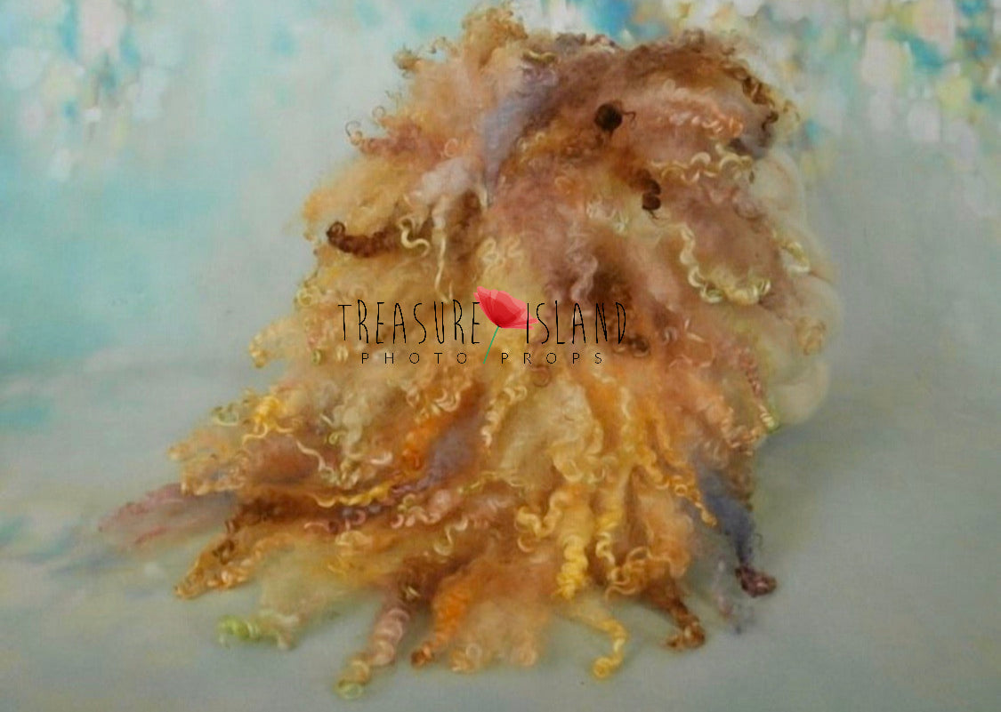 A prop designed to resemble a curly blanket with a mix of autumn colors, made of fabric, presented on a stand with a 'Treasure Island' logo in the corner.