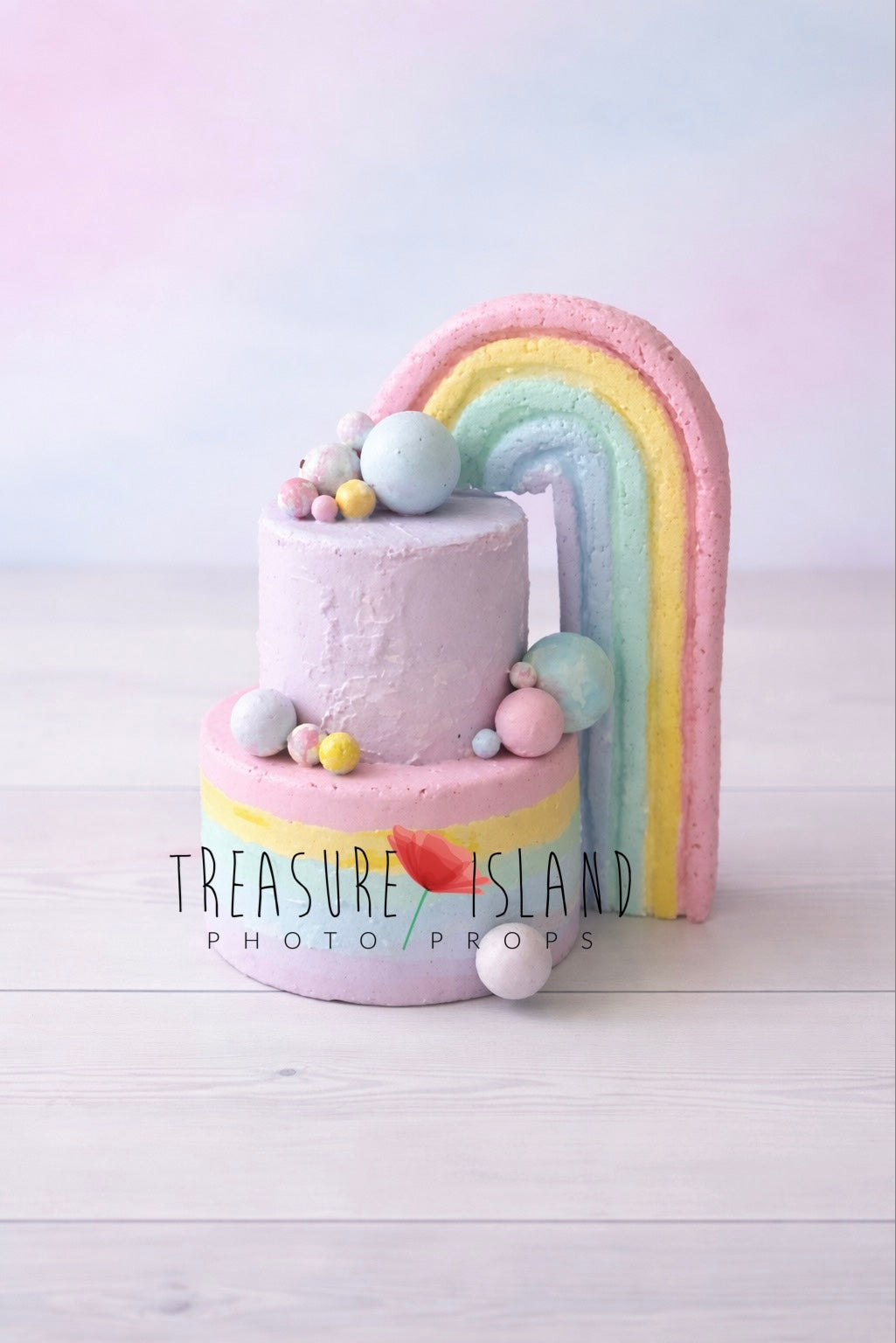 Pastel rainbow faux cake prop for cake smash photography, hand-painted two-tier design with decorative spheres, studio background
