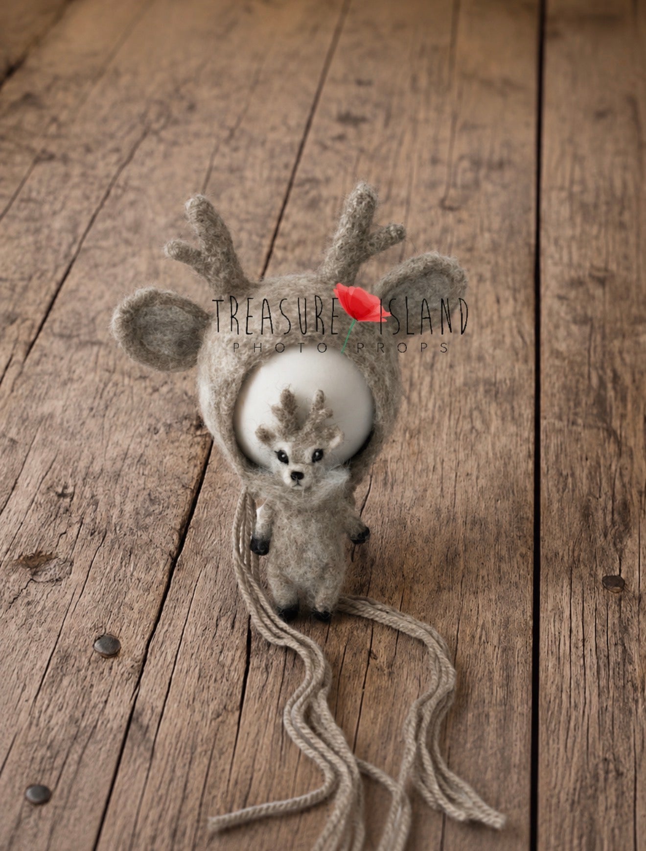 Close-up of handmade reindeer bonnet and miniature felted reindeer toy in natural taupe and beige tones
