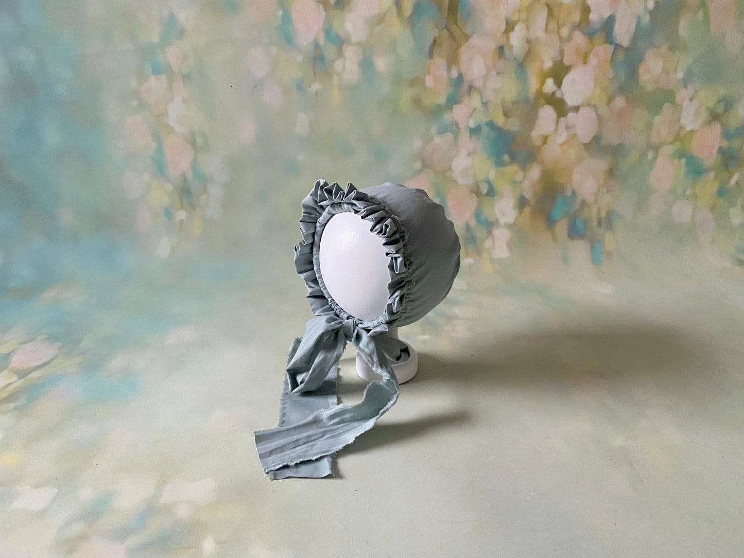 Susie vintage baby bonnet displayed against a soft fine art backdrop, with gathered ruffle and long handmade ties