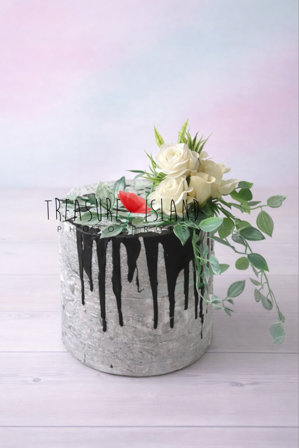 Concrete style faux cake prop with black drip icing and floral decoration for cake smash photography, studio background
