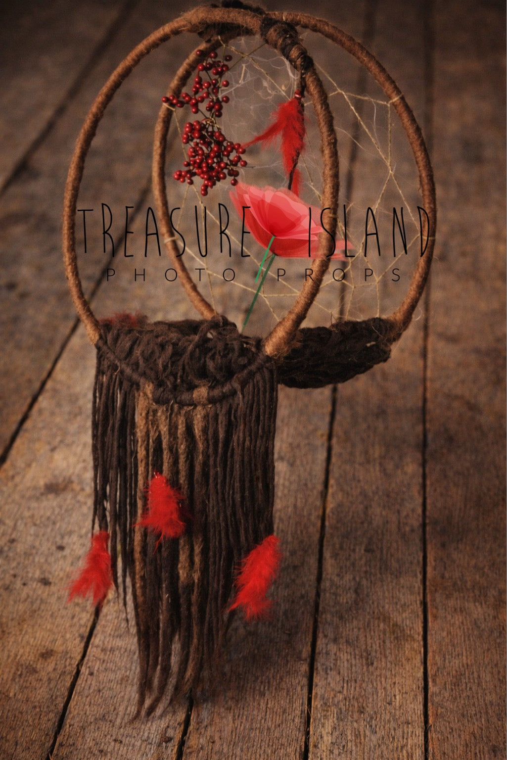 Handcrafted boho dream catcher with felted wool strands, red feathers and rowan accents styled against vintage wooden floor