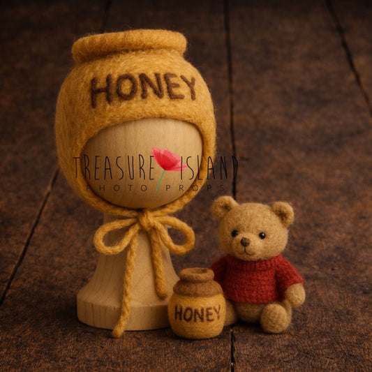 handmade honey pot newborn bonnet with wooden posing stand, teddy bear and felt honey jar on rustic wooden floor
