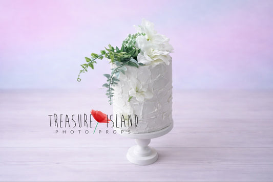 “White cake prop with cascading greenery on pastel background – Cake Smash photography prop