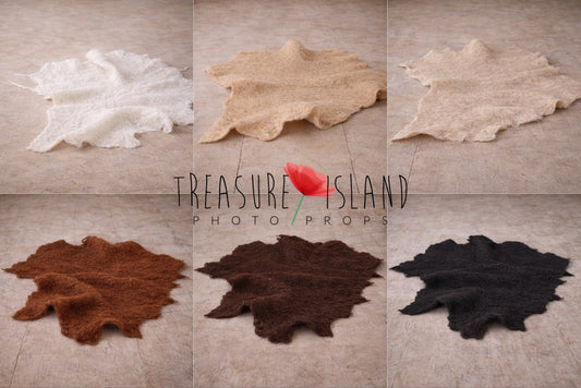 Hand-felted irregular wool blankets for newborn and sitter photography, available in white, sand, beige, rust copper, dark brown and black, displayed on wooden floor