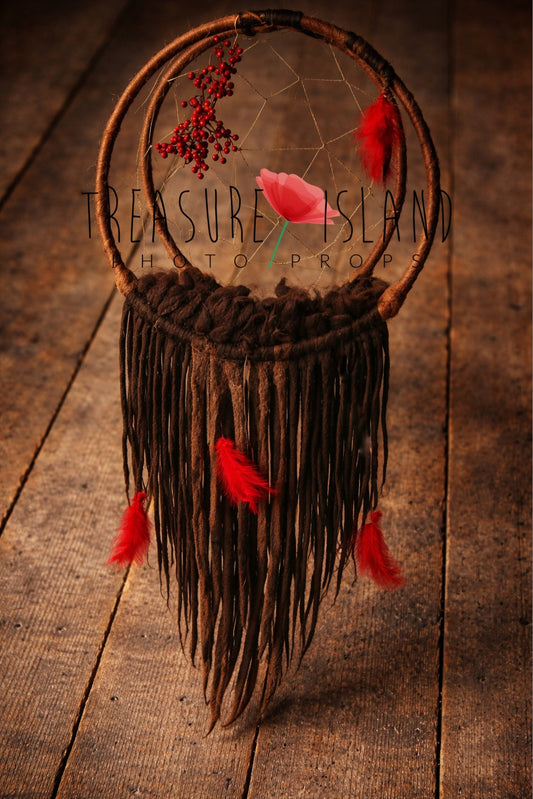 Boho hanging dream catcher photography prop with felted dreadlocks, red feathers and rowan berries on rustic wooden background.