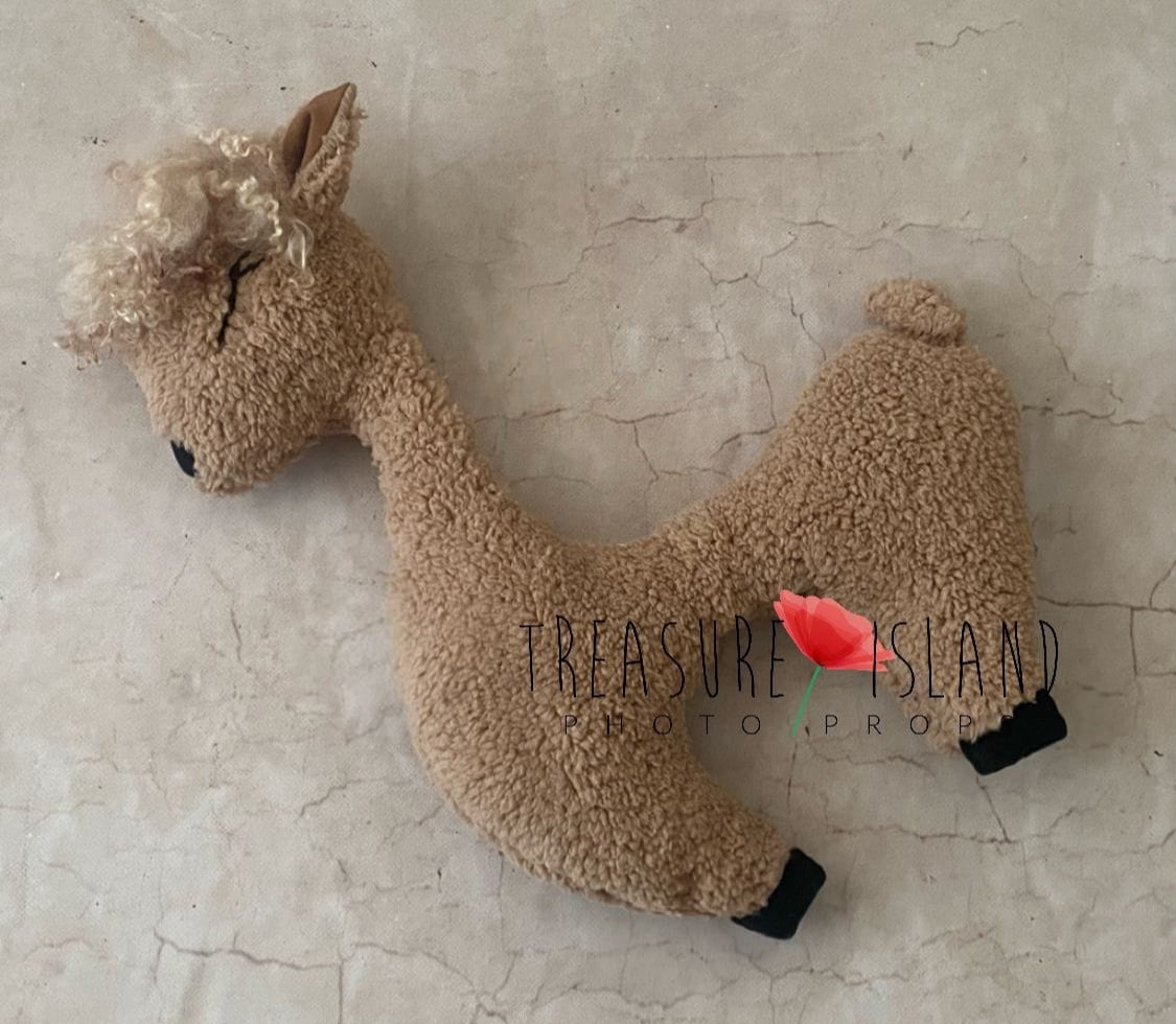 A beige alpaca posing pillow toy made of fluffy material, designed for photo props, with a logo and red rose in the bottom right corner.