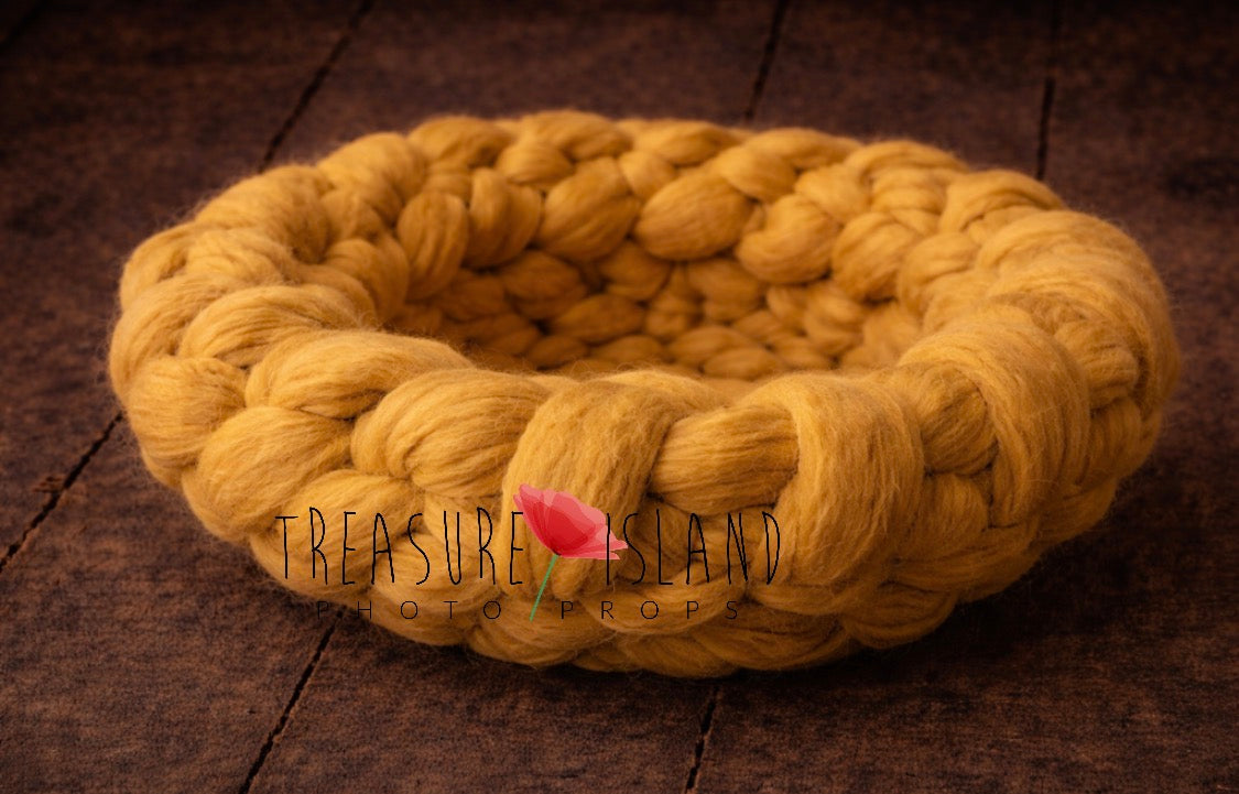 Close-up of chunky wool newborn photography nest in light orange showing thick knitted texture 