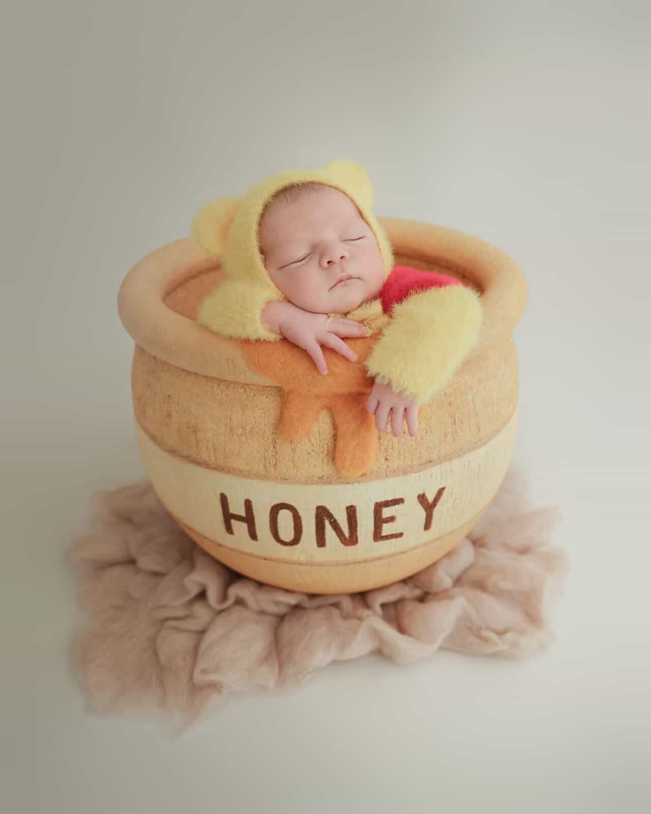Newborn posed inside a handmade honey barrel photography prop