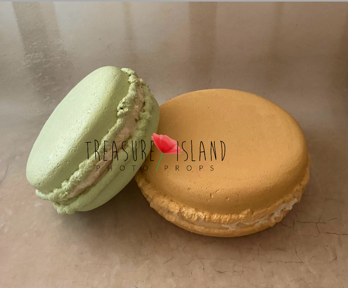 Two macarons, one mint and one mustard biscuit color, on a beige surface with 'Treasure Island Photo Props' branding.