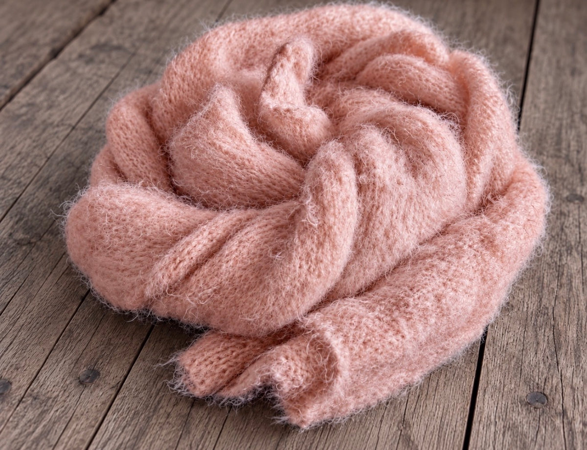 Dusty Pink long-haired knitted newborn photography wrap loosely gathered into a rounded shape, highlighting its fluffy volume and soft, layered folds