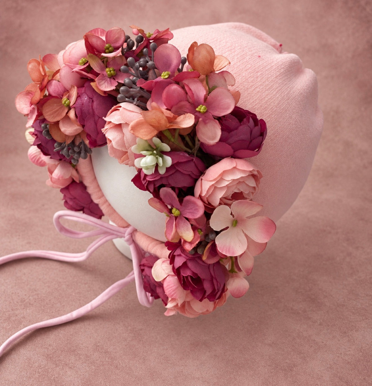 Close view of handmade dusty rose floral bonnet with berry blooms and botanical details