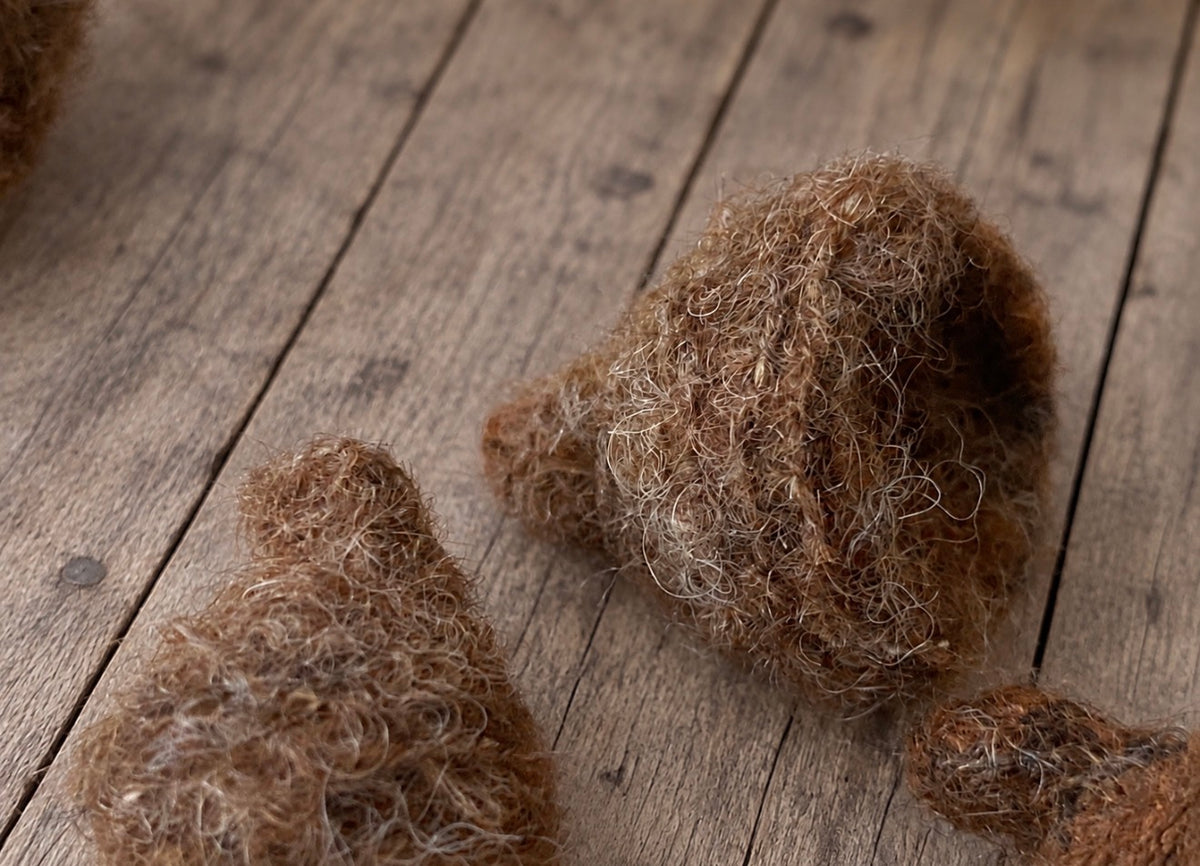 Close-up of handmade felted acorn caps showing the natural textured wool surface and handcrafted detail