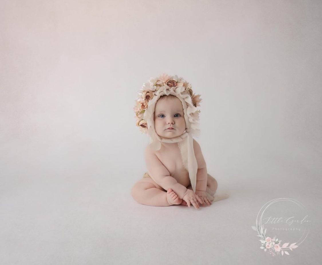 Sitter wearing a handmade romantic floral bonnet during a photography session