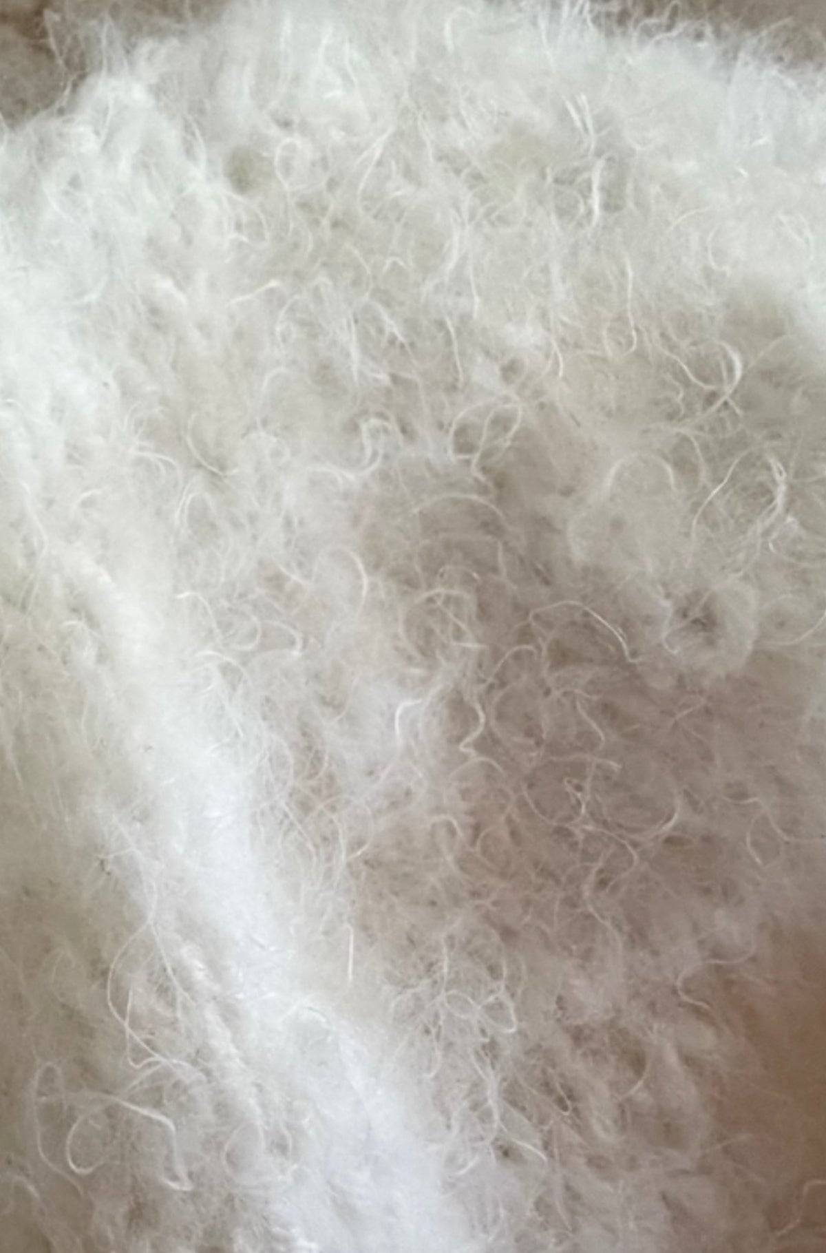 Extreme close-up of the soft, fluffy fibres and delicate surface texture of the ivory knitted photography bodysuit