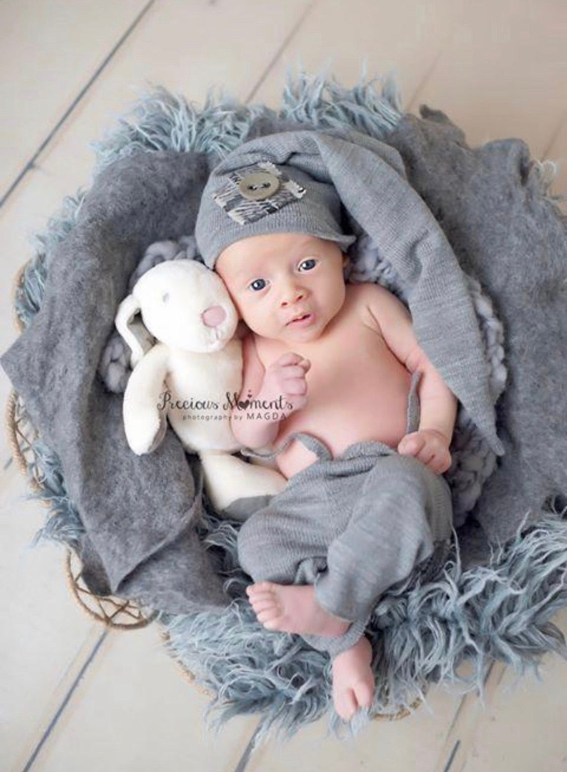 Grey hand-felted irregular wool blanket wrapped in soft organic folds around a newborn