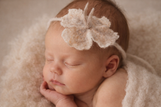 Newborn wearing a hand-felted wool flower headband for fine art baby photography
