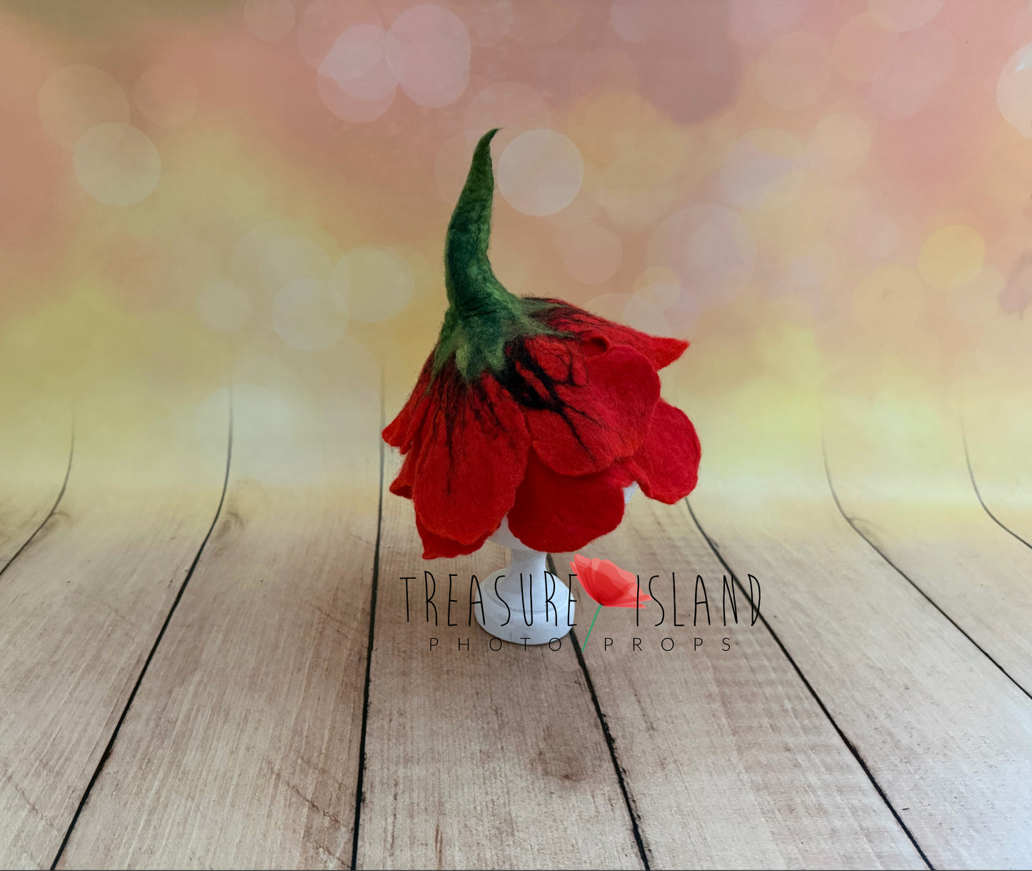 Side view of red hand-felted poppy flower bonnet with layered petals and green stem