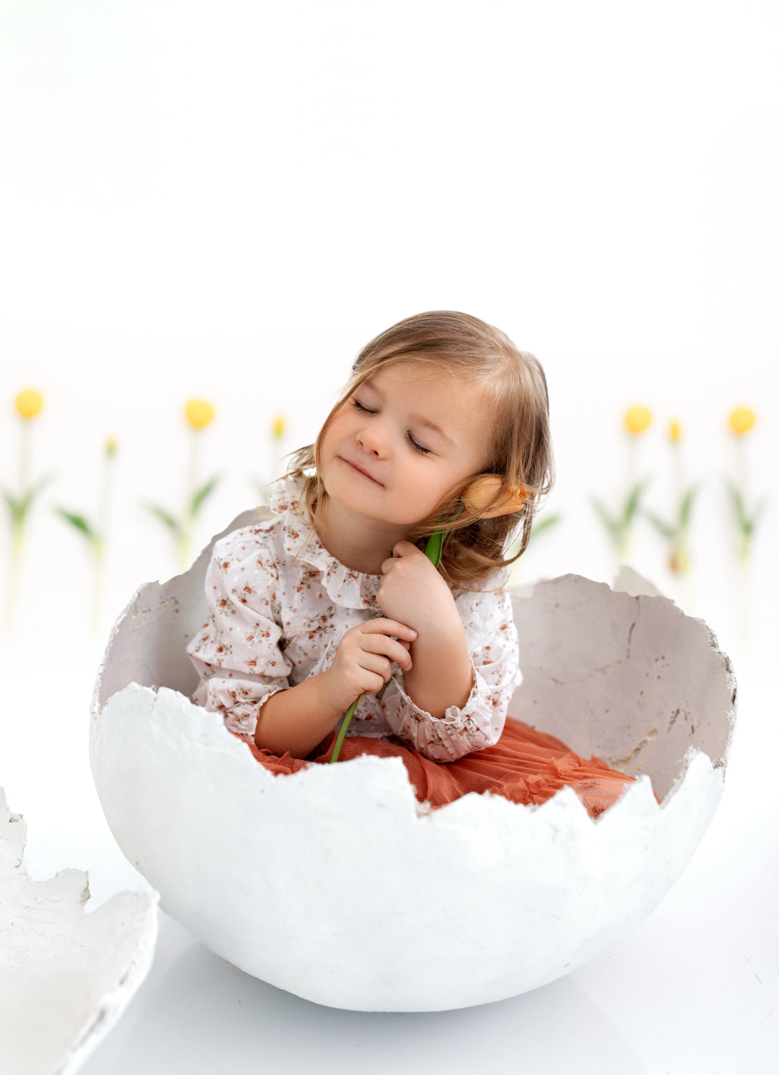 Sitter posed inside handmade plaster eggshell for spring and Easter photography