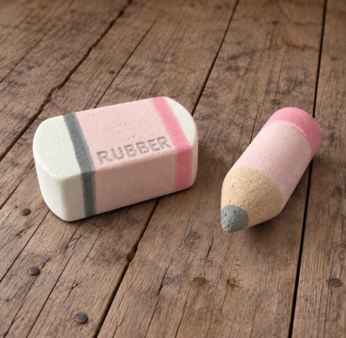 Handmade pink Styrofoam pencil and matching eraser with embossed RUBBER lettering, displayed together on a rustic wooden background