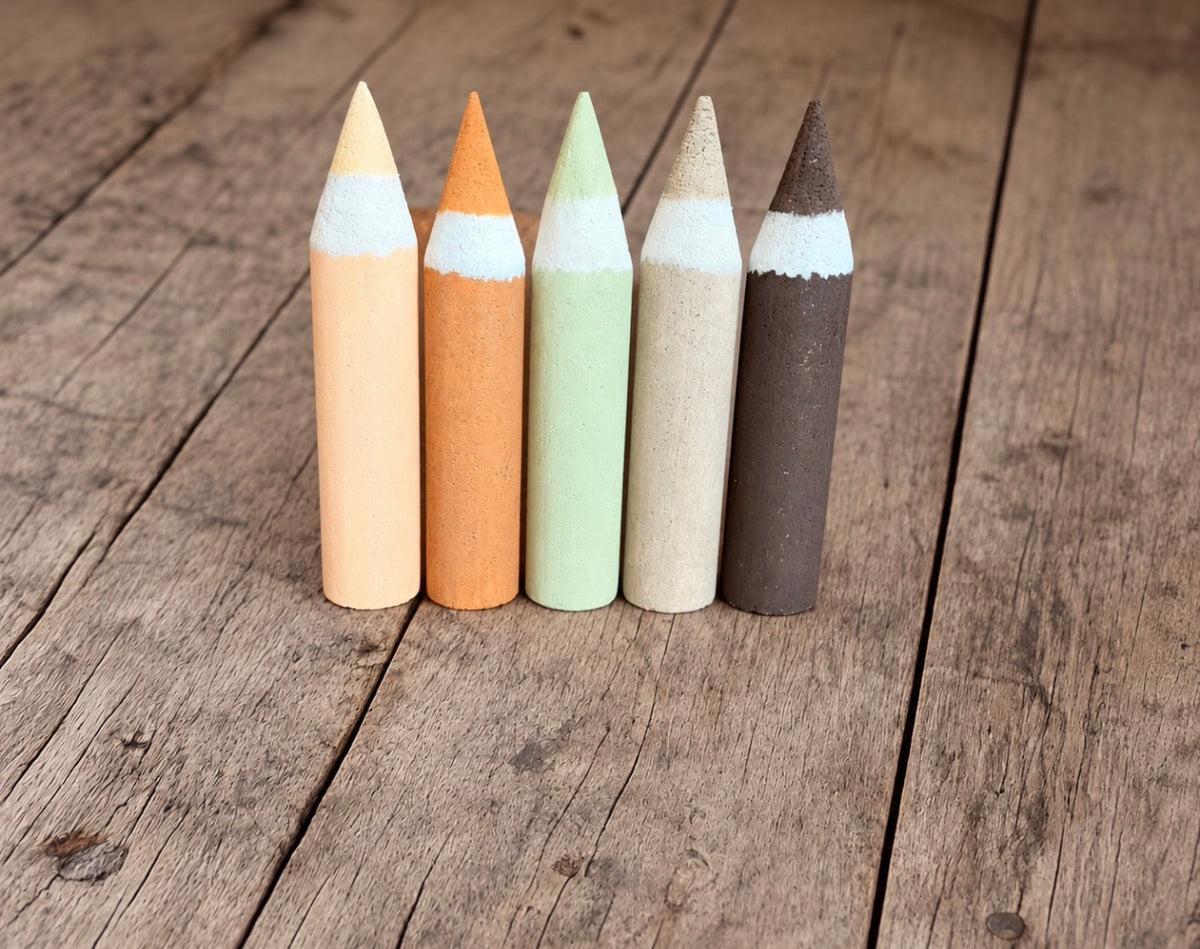 Five giant styrofoam crayons standing upright in pastel yellow, orange, mint, beige and brown, designed for school-themed photography