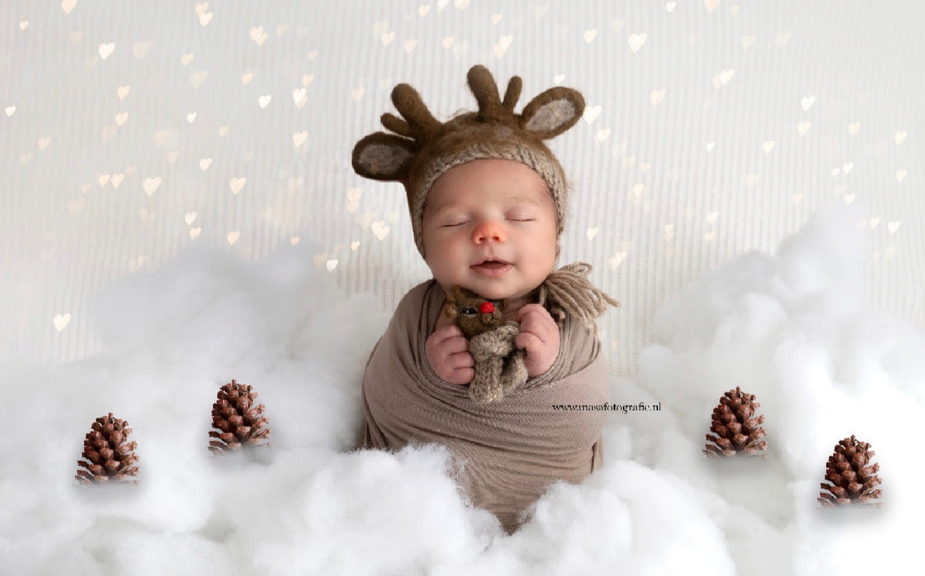 Newborn Christmas photography scene styled with reindeer bonnet and miniature felted red-nosed reindeer