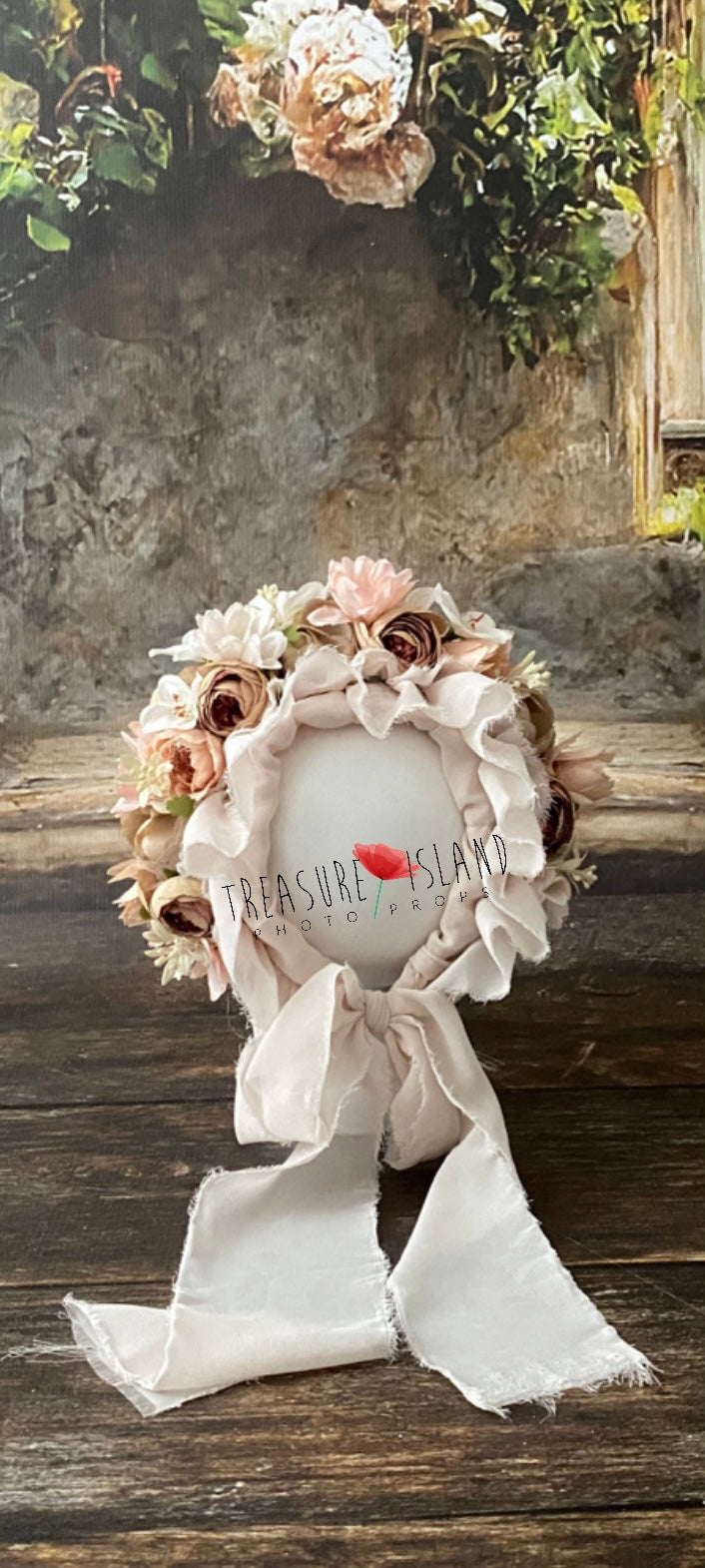 Close view of handmade floral bonnet showing layered blush, cream and warm-toned artificial flowers