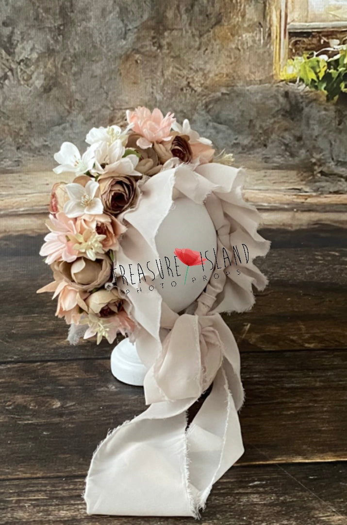 Close view of handmade sitter floral bonnet showing layered blush, cream and warm-toned artificial flowers