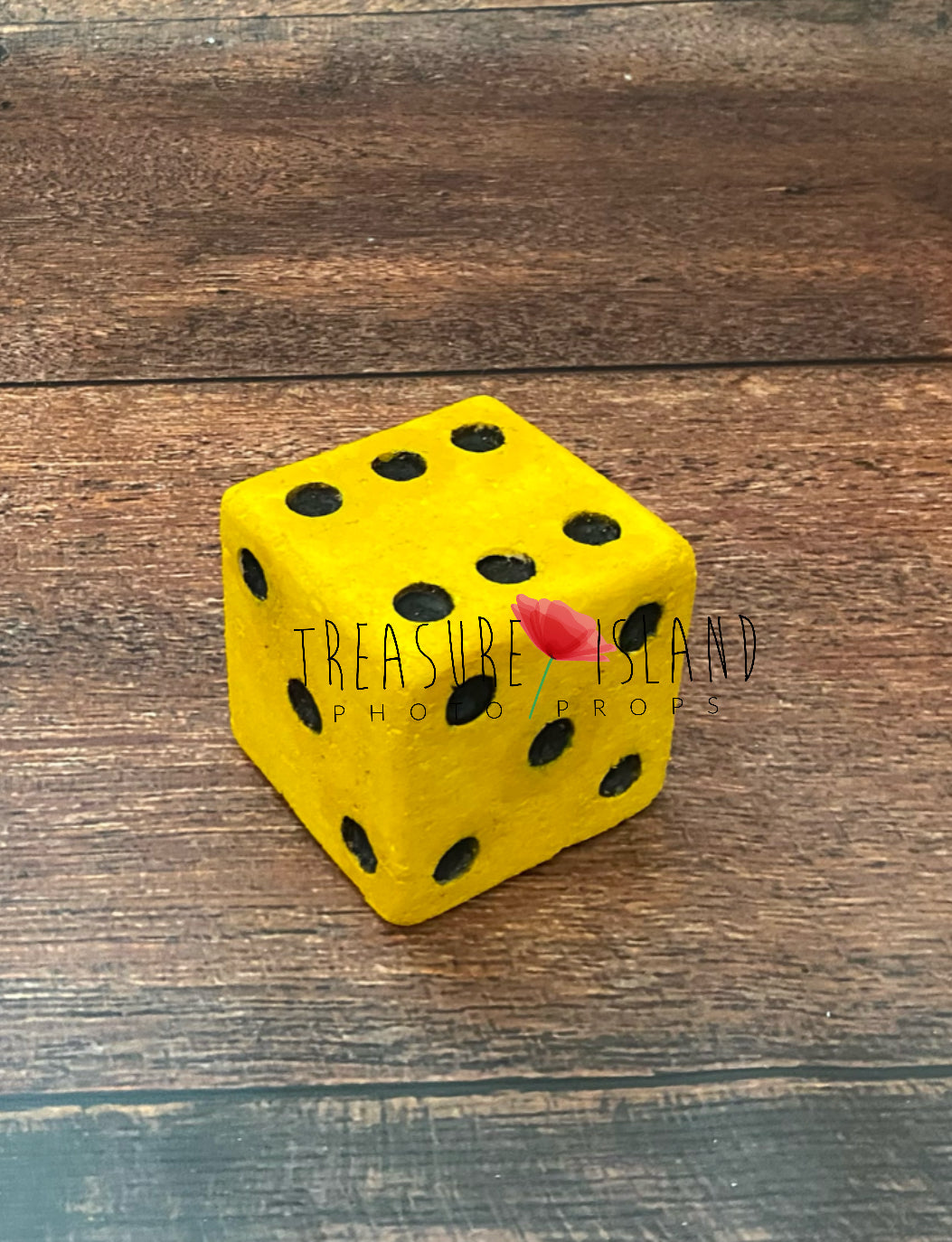 Yellow dice with black dots on a wooden surface, branded 'Treasure Island Photo Props'.