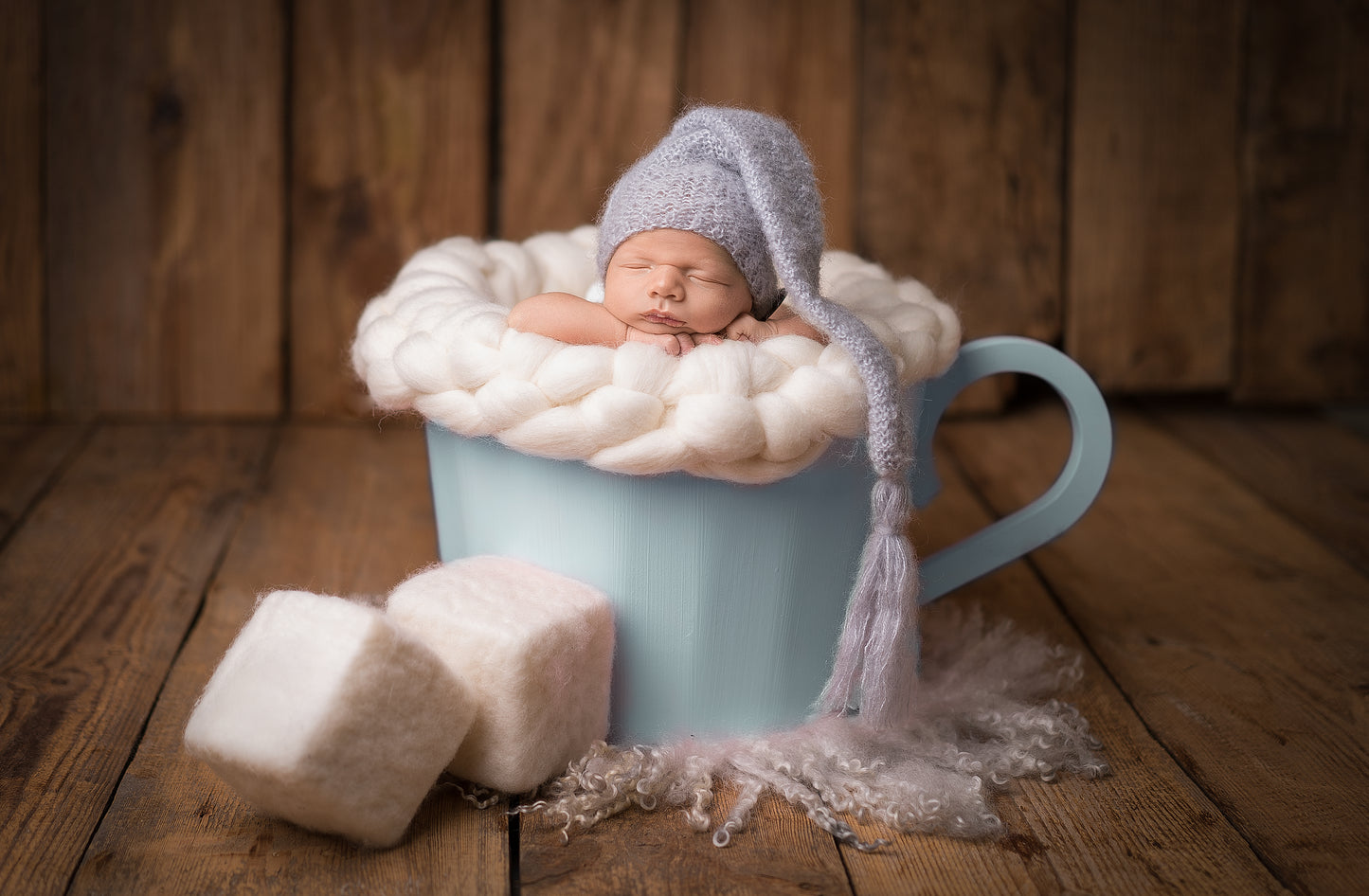 Chunky wool nest used as a textured newborn photography layer inside a wooden cup prop