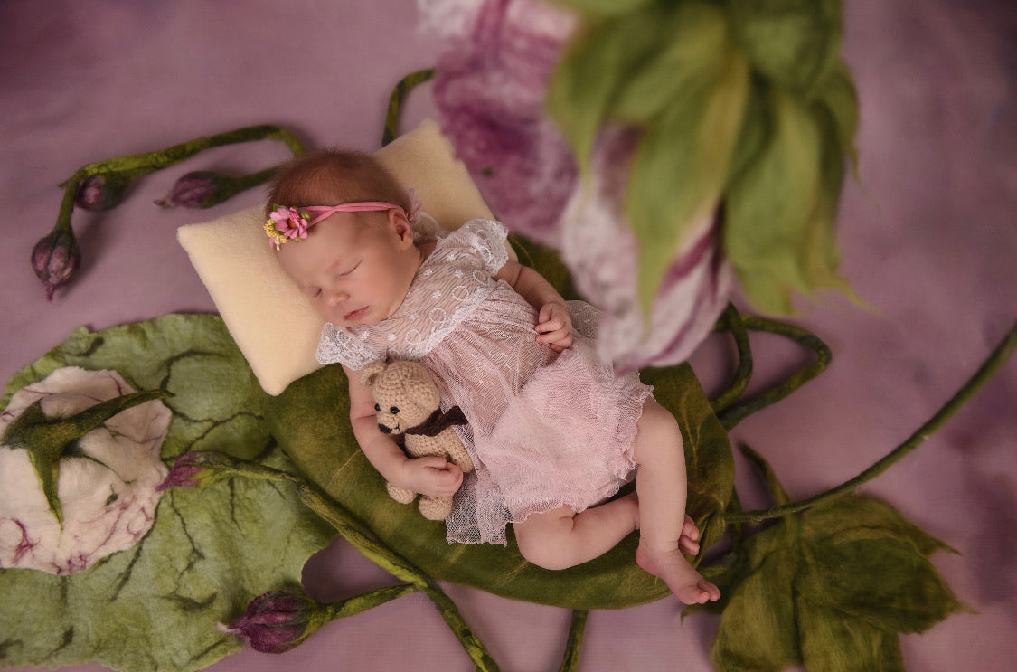 Newborn photography scene with Thumbelina wool nest and sculptural flower vine