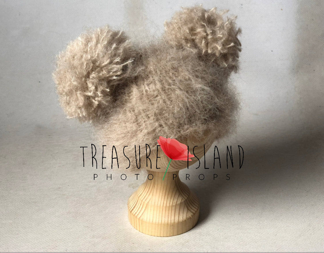 Beige knitted double pom pom hat styled as a baby photography prop
