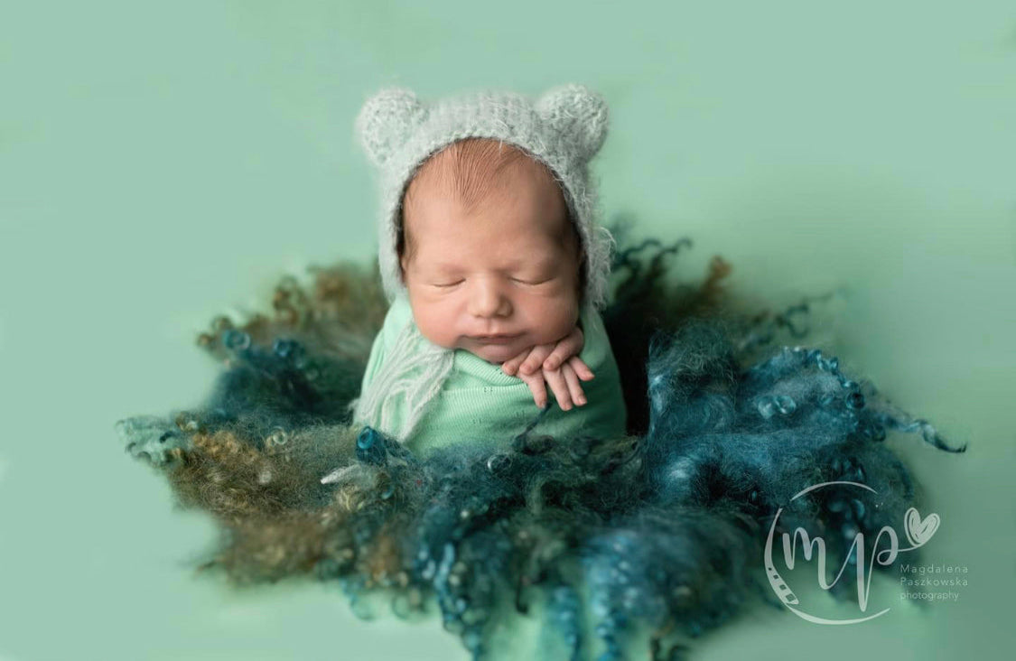 Newborn posed on Enchanted Forest curly wool blanket with rich teal and forest green sheep curls