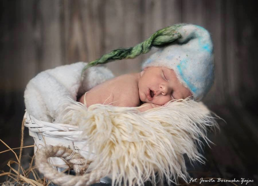 Newborn wearing a hand-felted white and blue twisted pixie hat with green tip